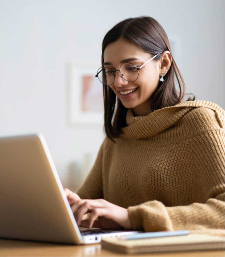 eine Frau mit Brille tippt auf ihrem Laptop